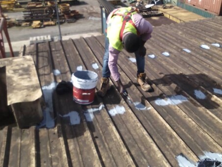 Worker carrying out roof repair work on a corrugated roof.